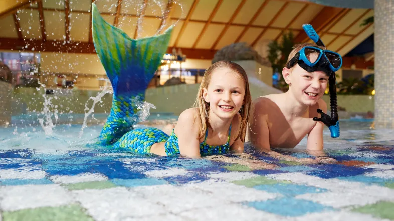 Zwei Kinder liegen im Wasser mit einer Flosse vom Aquafun Soest
