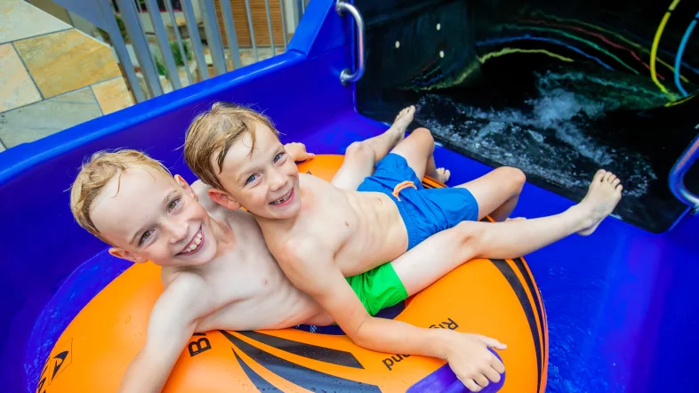 Zwei Kinder sitzen in einem Reifen vor dem Eingang der Reifenrutsche im Aquafun Soest.