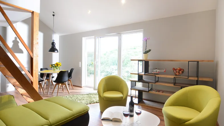 Ferienhaus Kat4 Wohnbereich grüne Sessel, heller Raum