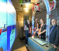 Gruppe bei einer Führungsrunde im Aquarius Wassermuseum Mülheim, geführt von einer Museumsperson vor multimedialer Ausstellung.