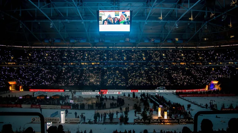 Leuchtende Beleuchtung beim Biathlon auf Schalke, die das Stadion in bunten Farben erstrahlen lässt.