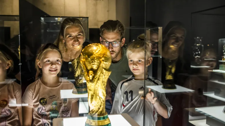 Familie schaut sich den Pokal in einer Vitrine an im Deutschen Fußballmuseum Dortmund,