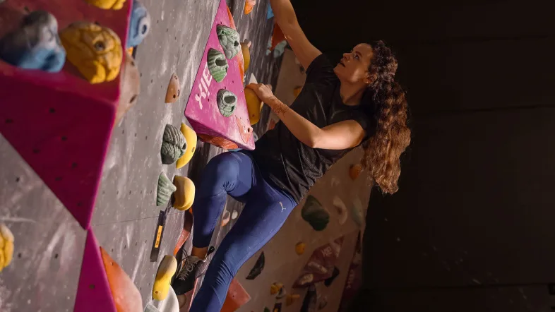 Frau klettert an einer Boulderwand in der Einstein Boulderhalle in Düsseldorf.