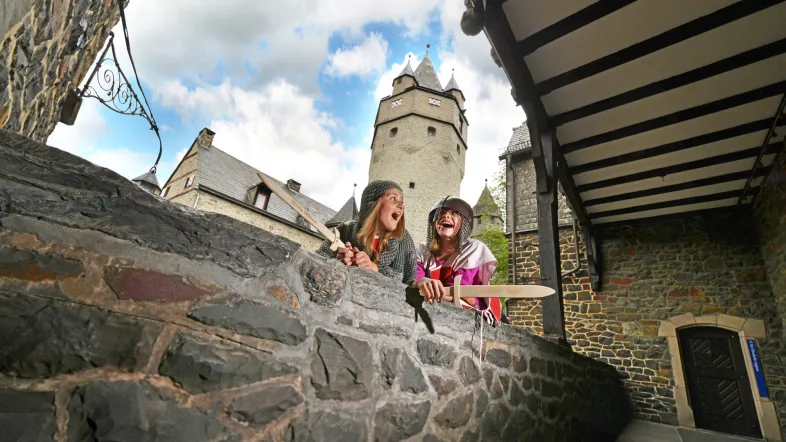 Kinder schauen über die Mauer der Burg Altena.