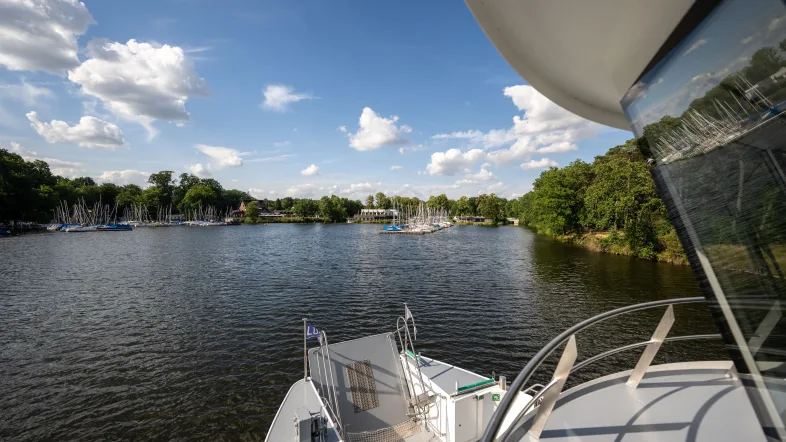 Das Bild wurde aus der Perspektive des Kapitäns fotografiert. Zu sehen ist ein Teil der äußeren Kapitänskabine und der Bug des Schiffes. Das Bild stellt das Anfahren der Haltestelle Stadtmühlenbucht dar, zu erkennen ist dies an ganz vielen kleineren Segelbooten, die an einem Steg fest gemacht sind.