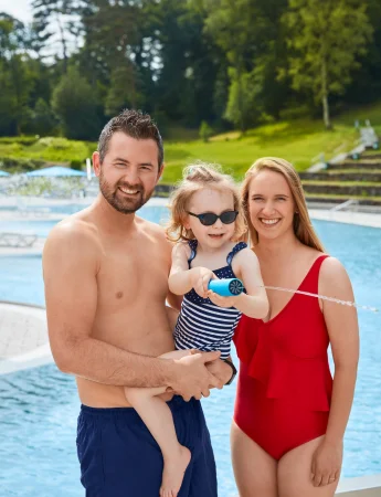 Familie steht gemeinsam am Beckenrand des Freibads Witten Annen und schaut in die Kamera.