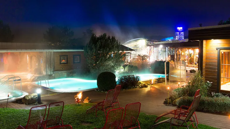 Außenbecken im Bad Heveney Witten mit klarem Wasser, Liegeflächen und grüner Umgebung.