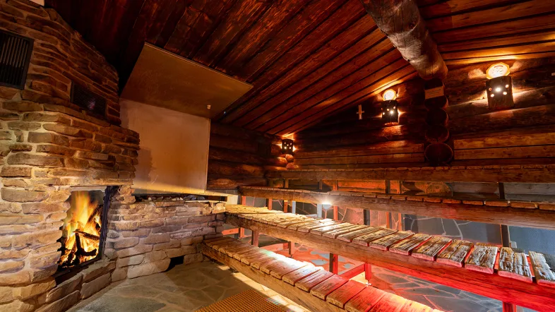 Innenansicht der Waldsauna im Revierpark Nienhausen mit Holzbänken und gedämpftem Licht für entspannte Atmosphäre.