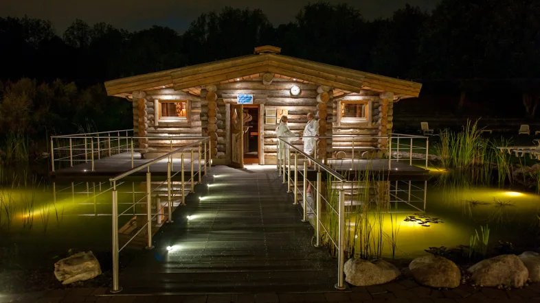 Beleuchteter Weg zur Sauna im Revierpark Vonderort bei Nacht, umgeben von Bäumen und ruhiger Atmosphäre.