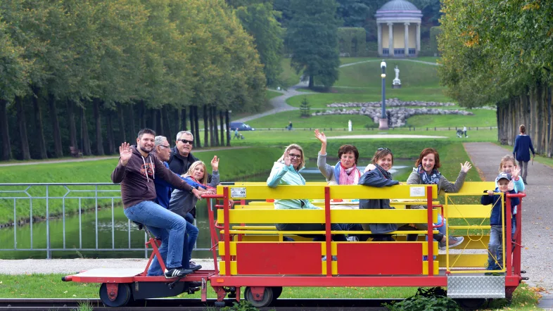 Familie auf einer Draisine winkt in die Kamera.