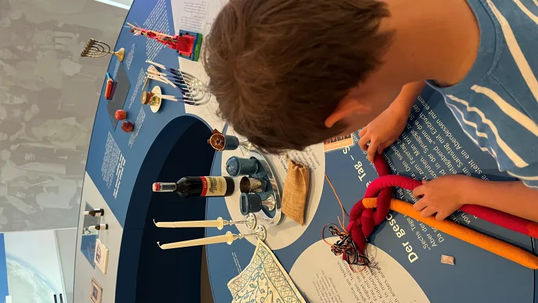 Junge im Jüdischen Museum Dorsten bindet einen Zopf.