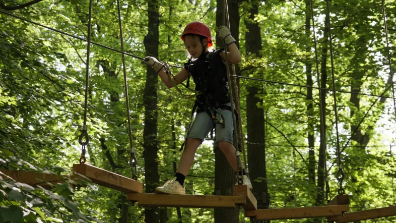 Mädchen mit Kletterausrüstung klettert konzentriert im Kletterpark Hamm.