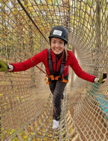 Eine Frau klettert durch einen Tunnel aus Seilen im Kletterwald Freischütz.