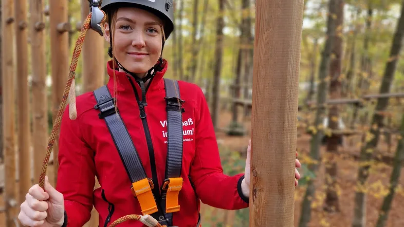 Frau kletter auf einer schwebenden Brücke im Kletterwald Freischütz.