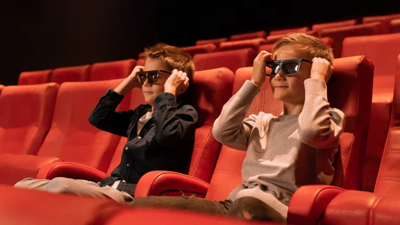 Zwei Kinder sitzen im Legoland in Oberhausen im Kino.