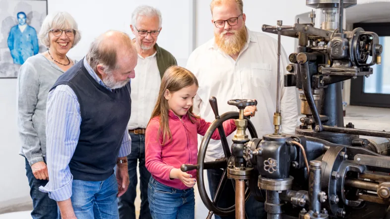 Eine Familie mit einem Kind betrachtet gemeinsam ein Ausstellungsstück im Kraftwerk engelskirchen.