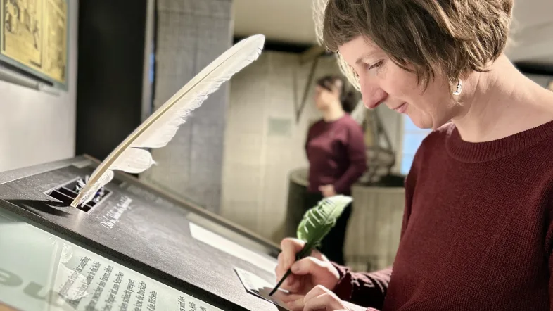 Besucherin am Tisch mit Feder und Tinte