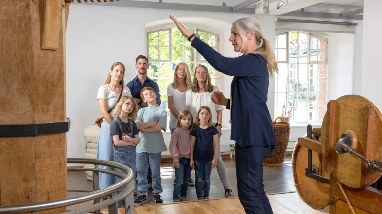 Eine Frau steht im Rahmen einer Führung im LVR-Industriemuseum Textilfabrik Cromford auf einem Podest.