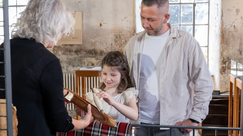 Kind probiert ein Ausstellungsstück im LVR-Industriemuseum Tuchfabrik Müller aus.
