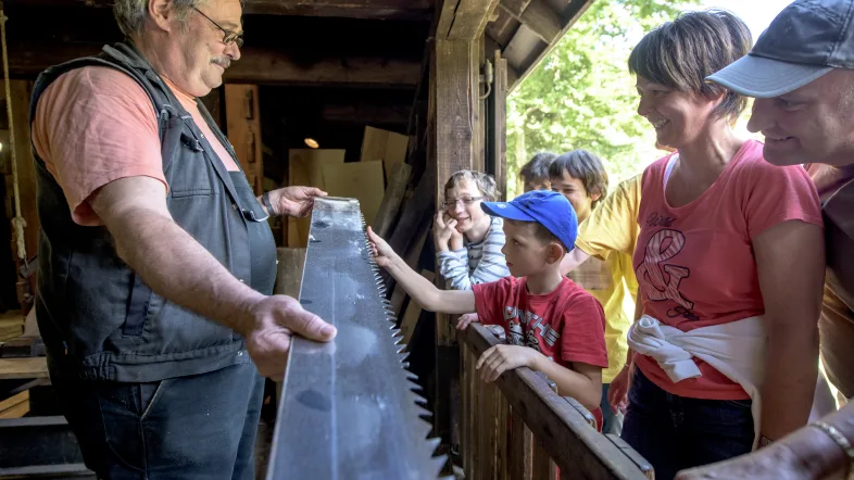 Gruppe von Menschen schaut sich im LWL-Freilichtmuseum Hagen – Westfälisches Landesmuseum für Handwerk und Technik das alte Sägewerk an.