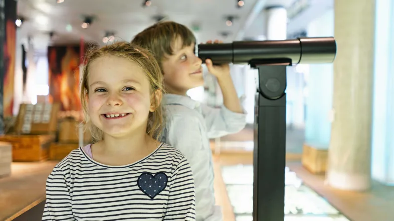 Kinder schauen durch ein Fernglas im LWL-Museum für Archäologie und Kultur in Herne.