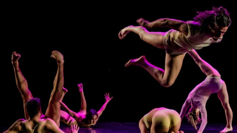 Tanzende Akrobaten auf der Bühne in lila Licht im Musiktheater im Revier in Gelsenkirchen.