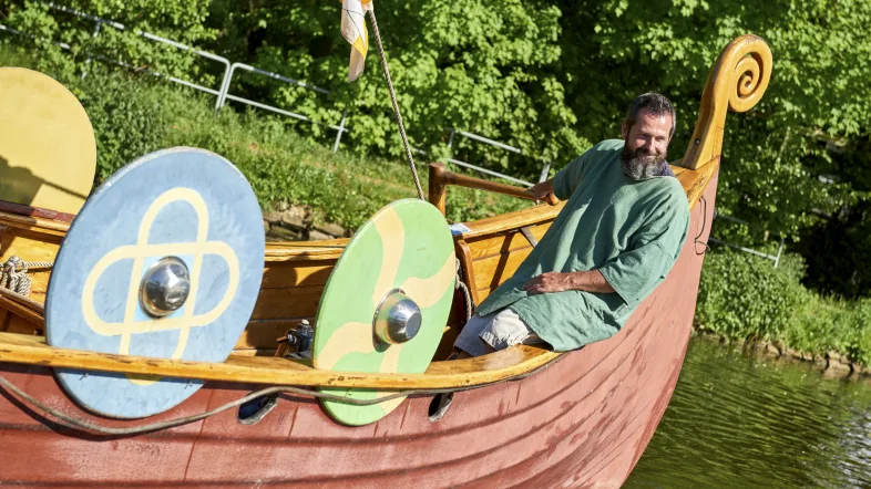 Mann in historischer Wikingerkleidung sitzt auf dem Wikingerschiff in Mülheim an der Ruhr.
