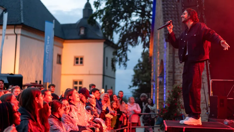 Sänger auf einer Bühne vor Publikum vor dem Haus Opherdicke.