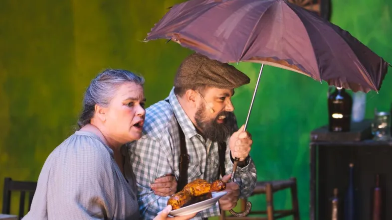 Ein Paar Schauspieler unter einem Regenschirm auf der Naturbühne Hohensyburg.