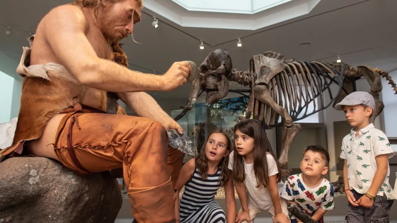 Neandertaler mit Skelett im Hintergrund im Naturmusem Dortmund.