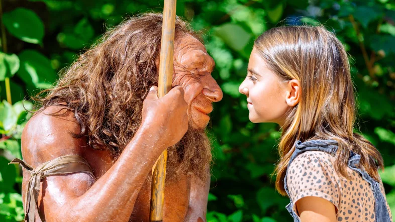 Mädchen schaut ins Gesicht einer Skulptur eines Neanderthalers im Neanderthalmuseum in Mettmann.