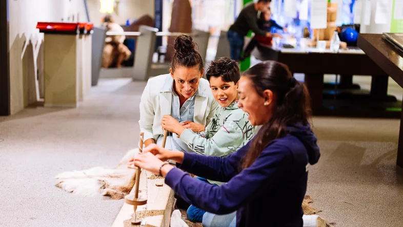 Eine Familie probiert die Steinzeitbohrer in der Ausstellung des Neanderthal Museum aus