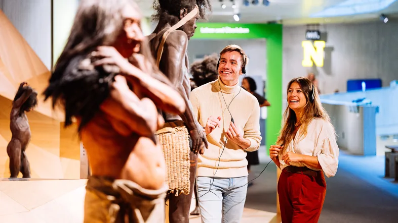 Zwei Erwachsene im Museum betrachten Rekonstruktionen unserer menschlichen Vorfahren
