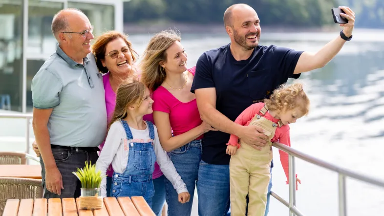 Familie macht ein fröhliches Selfie auf dem Ausflugsboot während einer Schifffahrt auf dem Biggesee.