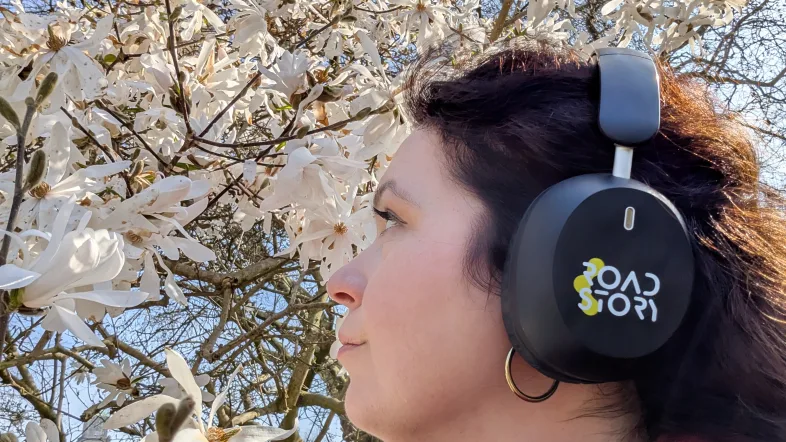 Frau mit Kopfhörern unter einem blühenden Baum.