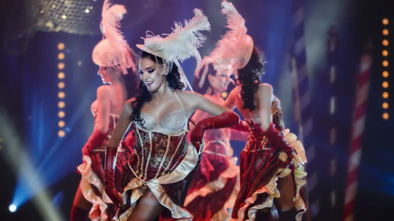 Mehrere Tänzerinnen in roten Kleidern auf der Bühne des Roncallis Apollo Varieté.