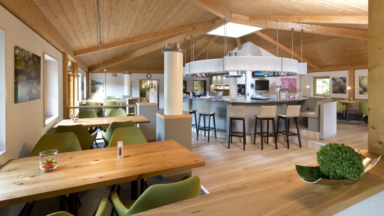 Saunadorf Lüdenscheid von innen mit viel Holz, grünen Sesseld und einigen Stüheln an einer Theke.