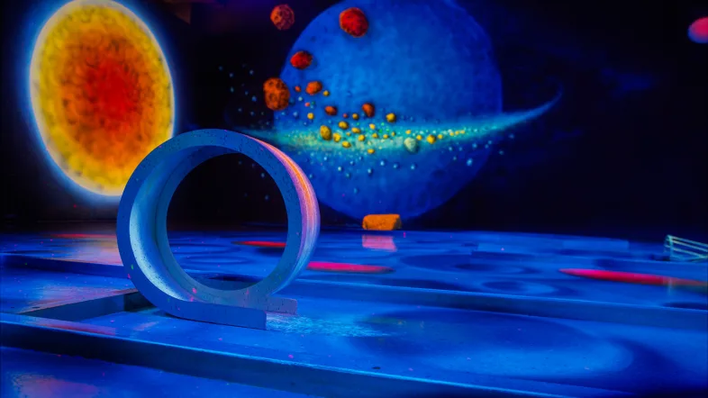 Loop-Bahn im Schwarzlicht-Semester Arnsberg mit leuchtenden Planeten im Hintergrund.