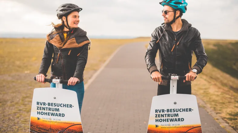 Paar auf Segways auf der Halde Hoheward in Herten, das sich liebevoll anschaut.