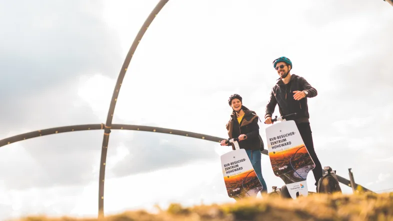 Paar fährt gemeinsam mit Segways auf der Halde Hoheward in Herten.