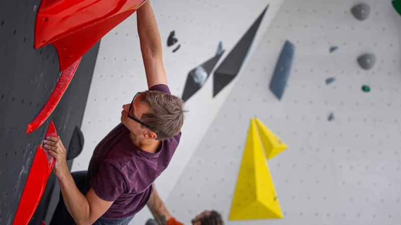 Mann klettert an Boulderwand.