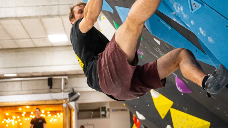 Mann klettert an Boulderwand.