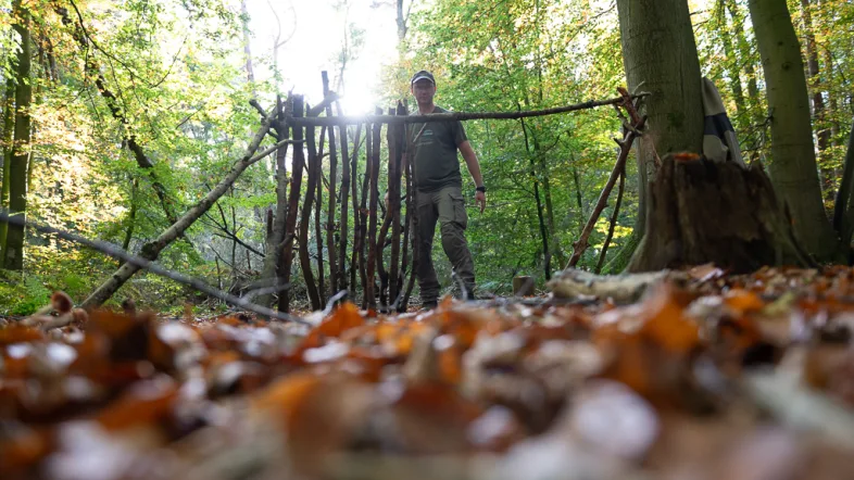 Mann baut mithilfe von Stöckem einen Unterschlupf