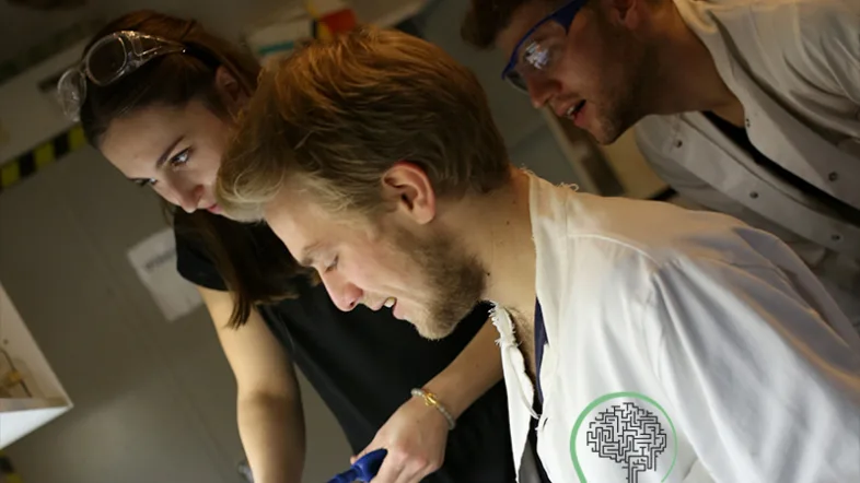 Menschen in Kitteln arbeiten gemeinsam in einem Escape-Room bei Think Escape Bochum.