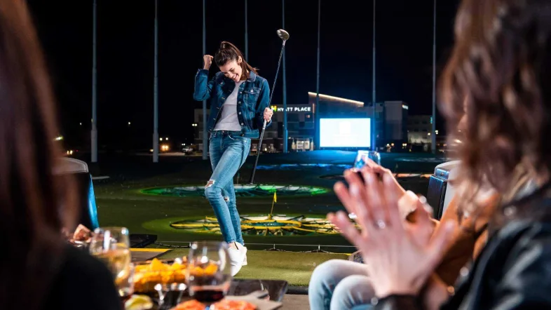 Frau jubelt nach einem erfolgreichen Schlag bei Topgolf Oberhausen.