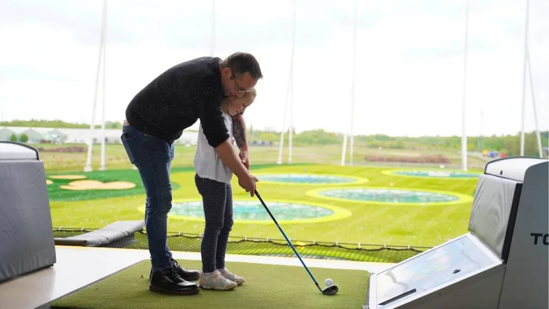 Vater und Tochter spielen gemeinsam bei Topgolf Oberhausen.