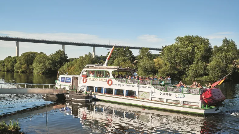 Ausflugsschiff der „Weißen Flotte“ Mülheim fährt unter einer Brücke auf dem Fluss entlang.