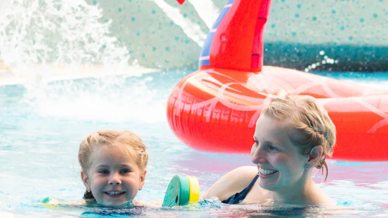 Kind und Mutter mit Schwimmtier im Becken