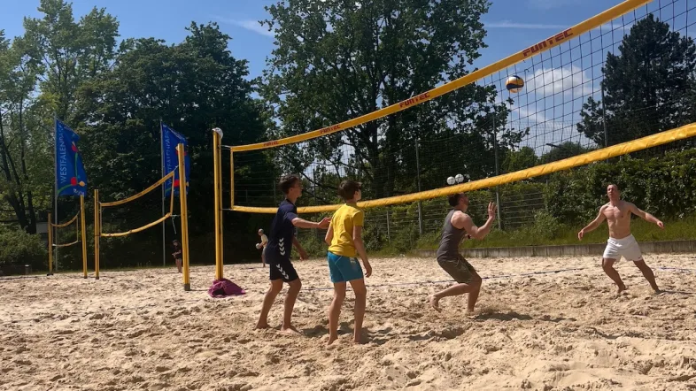 Menschen spielen Beachvolleyball im Westfalenpark Dortmund bei strahlendem Sonnenschein.