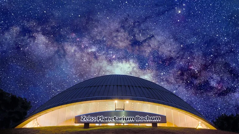 Das Planetarium Bochum bei Nacht, darüber ein klarer Sternenhimmel mit funkelnden Sternen.